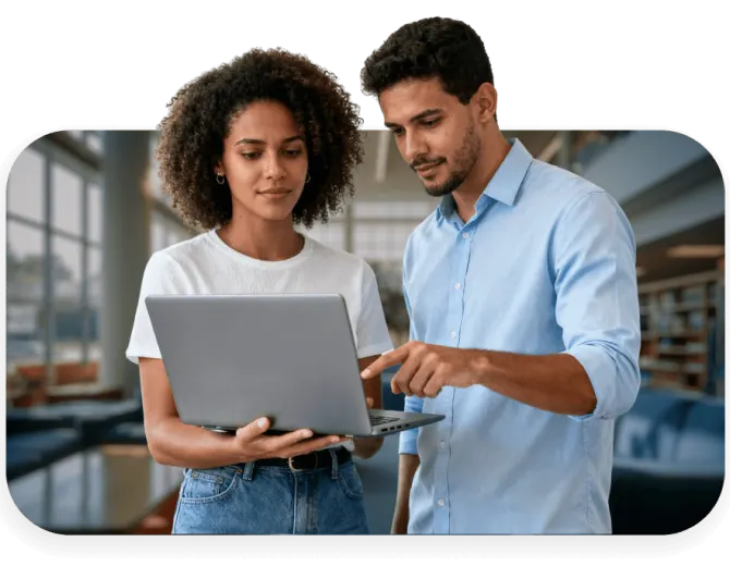 Uma estudante segura um notebook enquanto um colega aponta para a tela